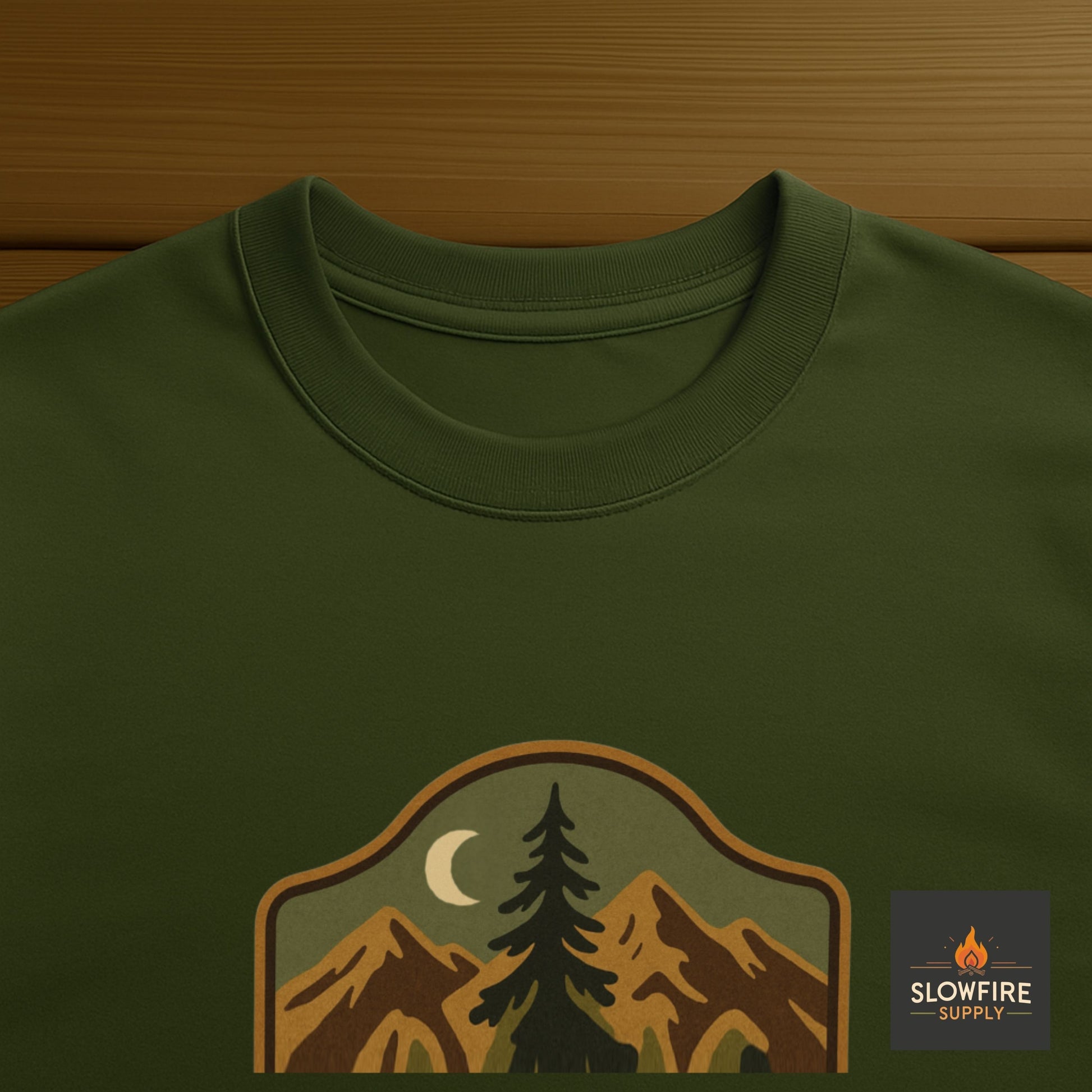 Green t-shirt with nature-themed graphic and 'Slowfire Supply' logo on a wooden surface