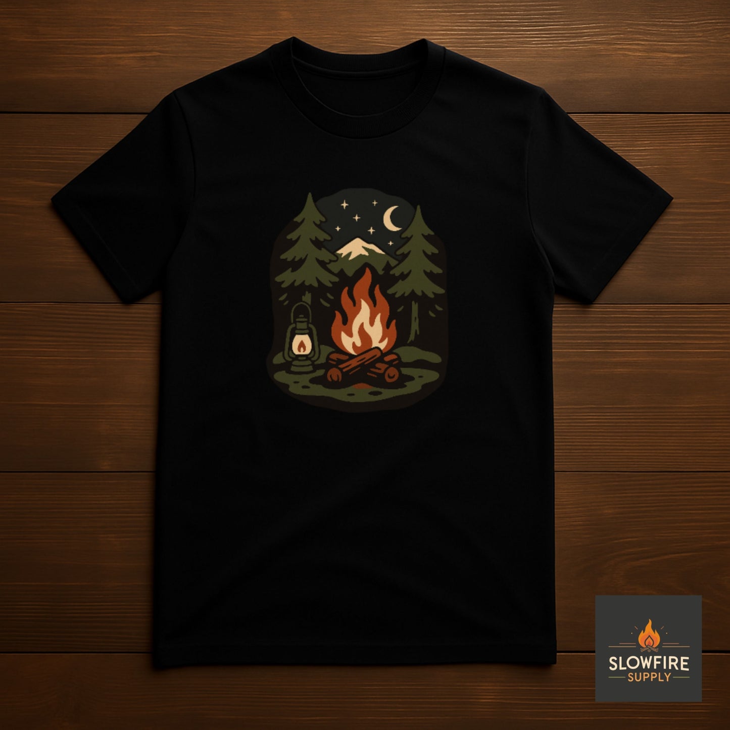 Black t-shirt with a campfire graphic on a wooden surface, featuring the Slowfire Supply logo.
